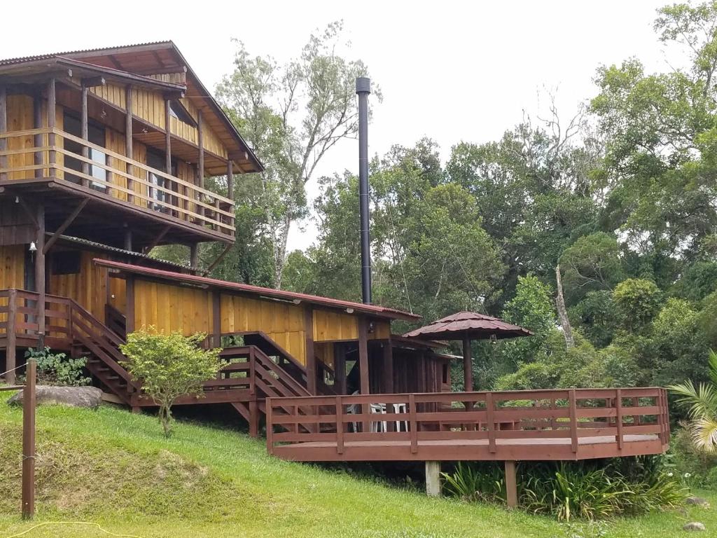 a wooden house with a balcony and an umbrella at Holo Pousada Vale Encantado in Rancho Queimado