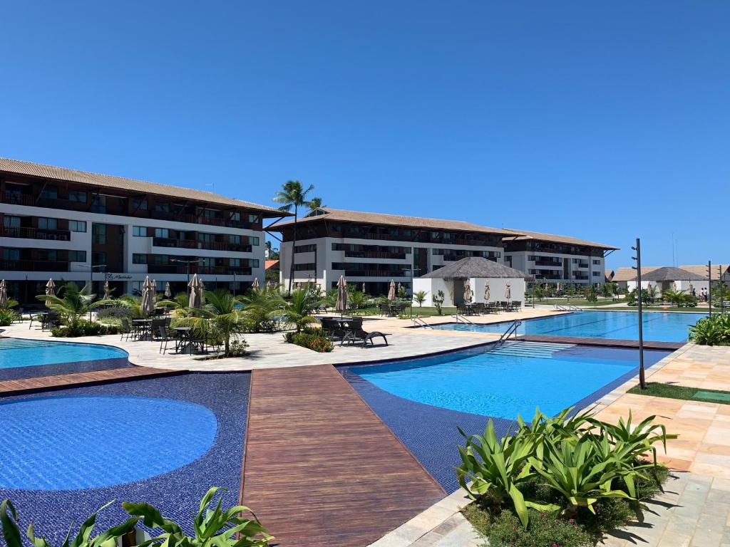 um resort com uma grande piscina e alguns edifícios em Flat Extraordinário Beira Mar em Porto de Galinhas com pé na areia Cupe Beach Living em Porto de Galinhas