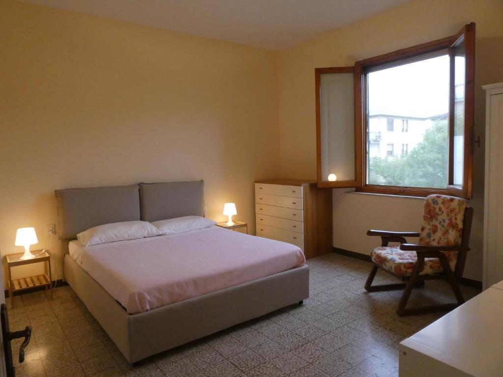 a bedroom with a bed and a chair and a window at Casa storica e confortevole in Empoli