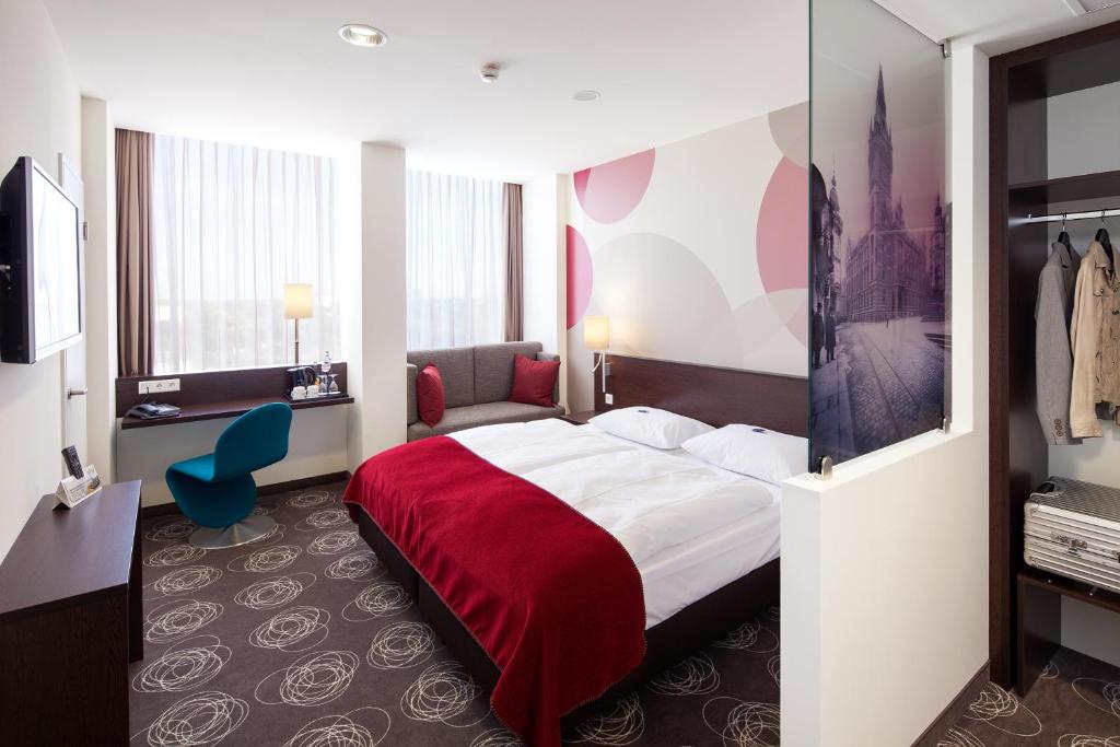 ein Hotelzimmer mit einem Bett mit einer roten Decke in der Unterkunft Webers - Das Hotel im Ruhrturm, Stefan Weber GmbH in Essen