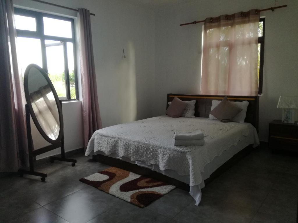 um quarto com uma cama, um espelho e uma janela em JKB Villa em Pamplemousses Village