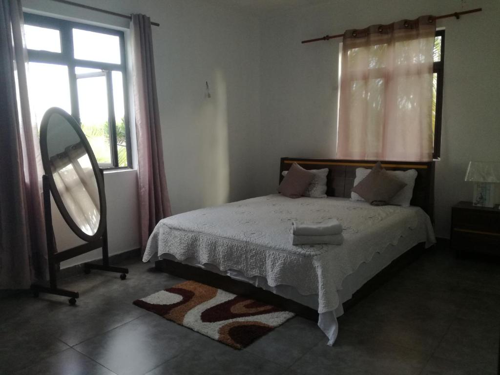 Schlafzimmer mit einem Bett, einem Spiegel und einem Fenster in der Unterkunft JKB Villa in Pamplemousses Village