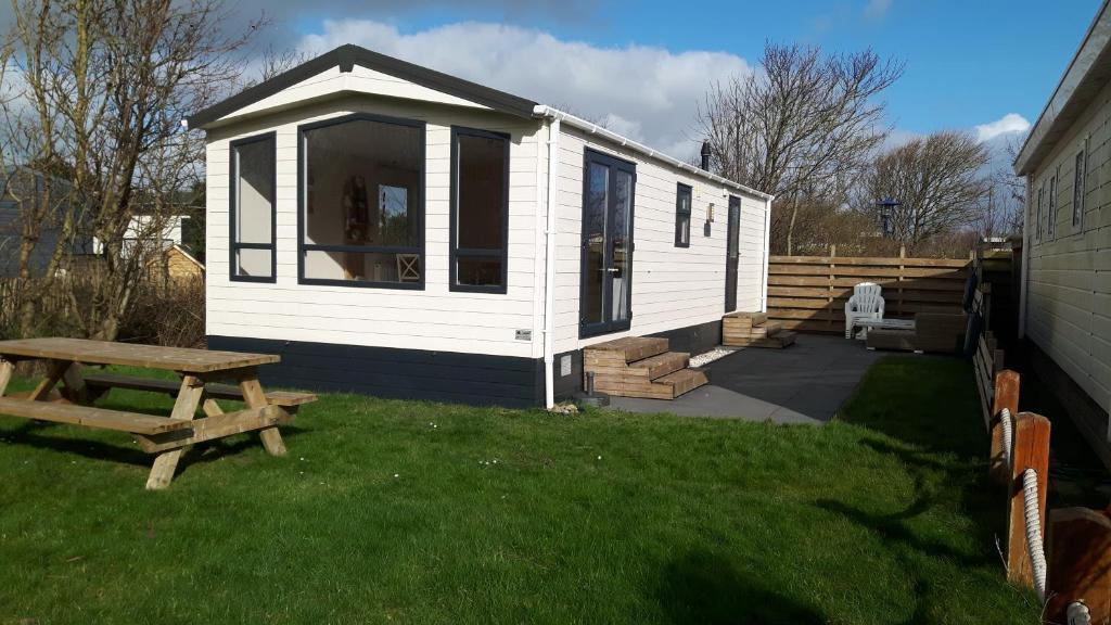 a white tiny house with a picnic table in a yard at Chalet Casa Quak in Petten