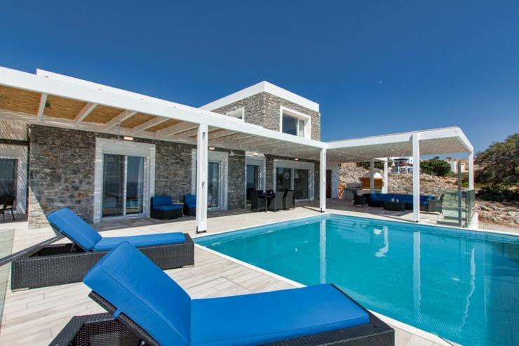 a swimming pool with blue chairs and a house at Villa Sophia in Pefki Rhodes