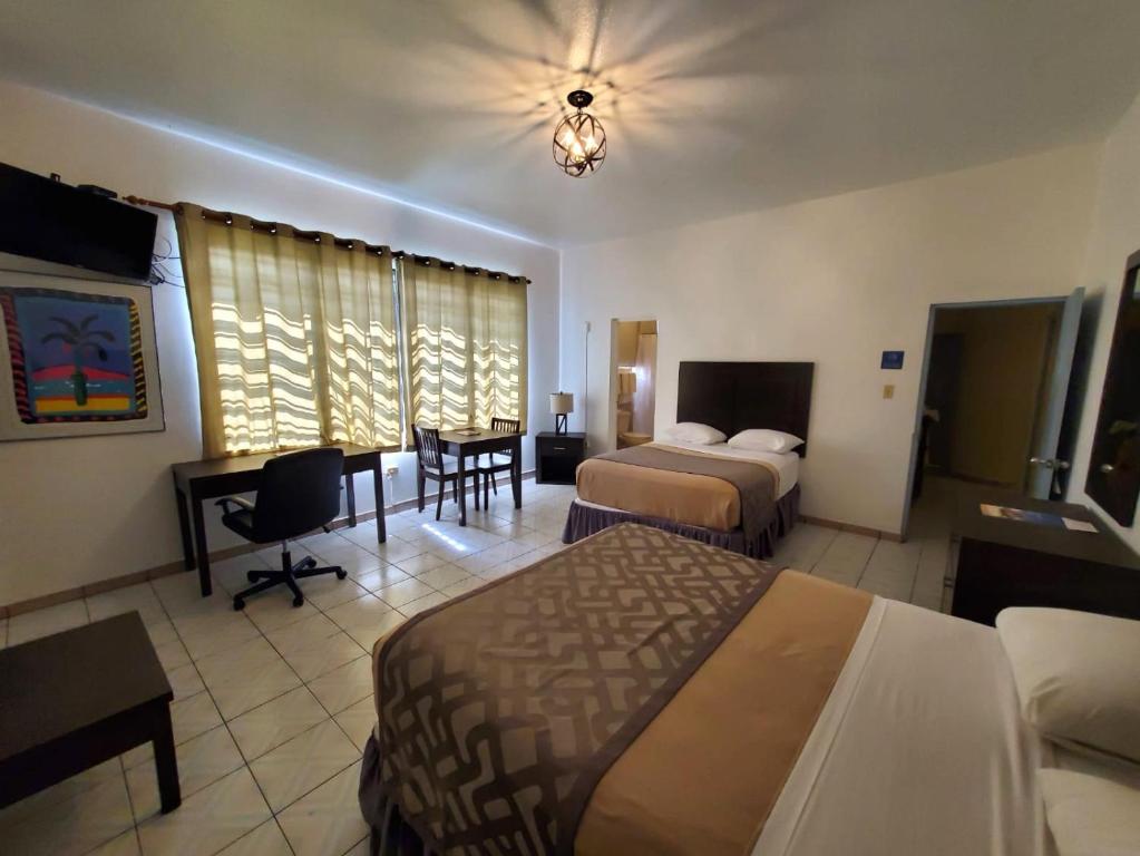 a hotel room with two beds and a desk at Borinquen Beach Inn in San Juan