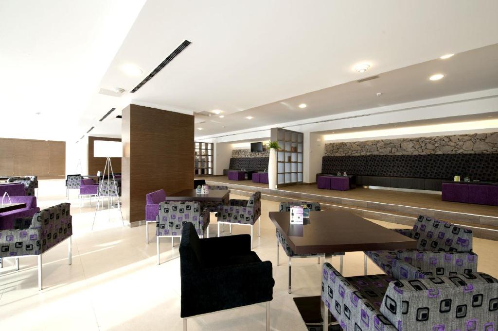 a restaurant with tables and chairs and purple chairs at Hotel Mediteran Plava Laguna in Poreč