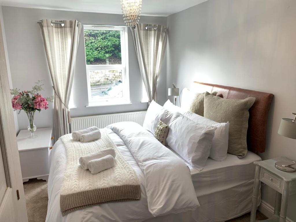 a bedroom with a bed with white sheets and a window at Spacious 2 Bed Apartment With Off Street Parking in Bath