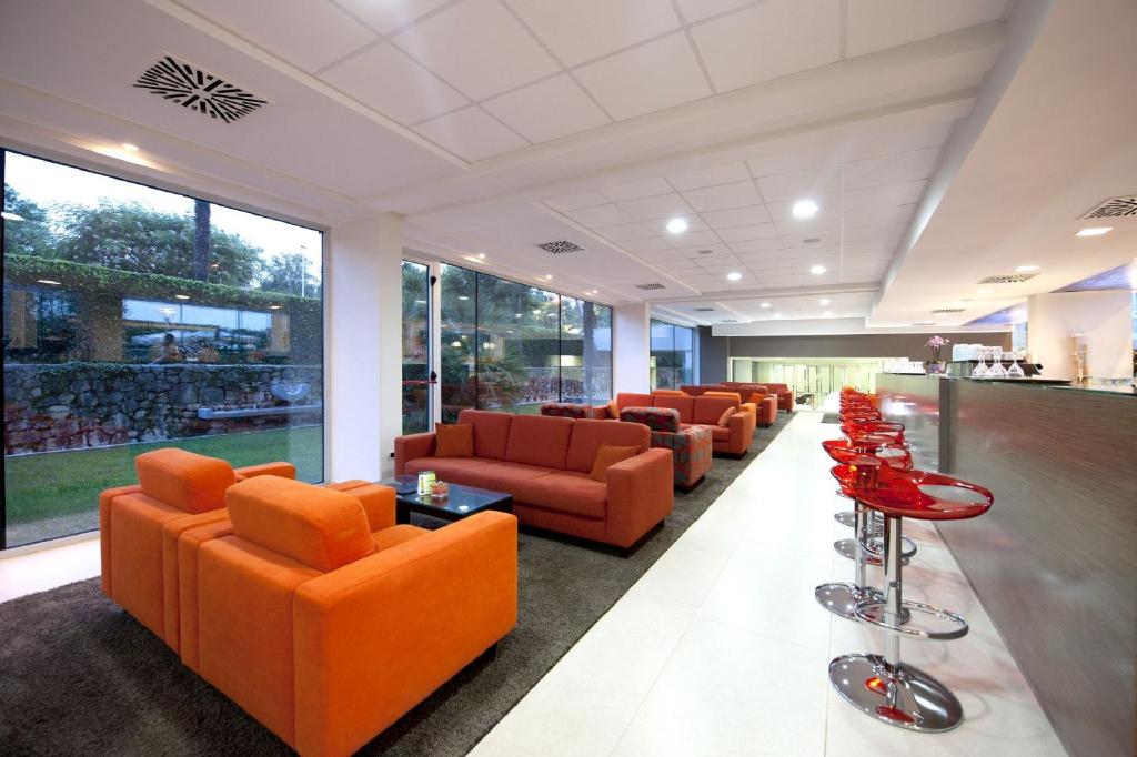 a waiting room with orange chairs and tables at Hotel Mediteran Plava Laguna in Poreč