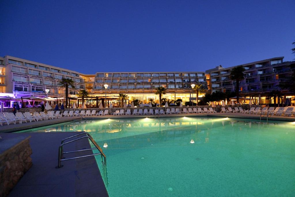 a large swimming pool in front of a building at night at Hotel Mediteran Plava Laguna in Poreč