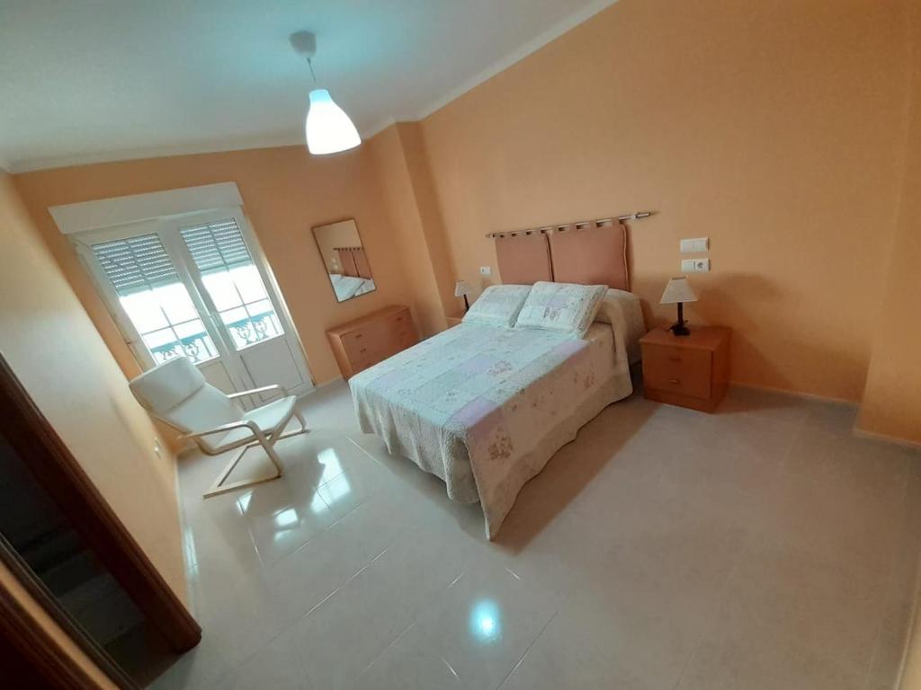1 dormitorio con 1 cama y 1 silla en Apartamento Playa da Langosteira, en Finisterre