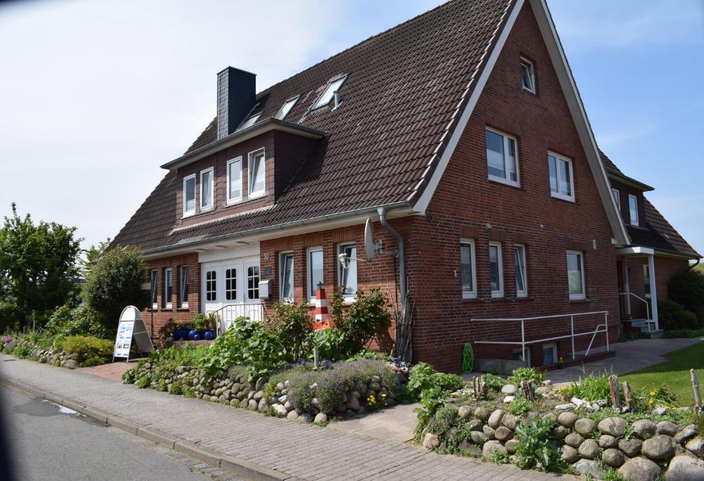 una grande casa in mattoni con un giardino di fronte di Hotel Haus am Meer a Büsum