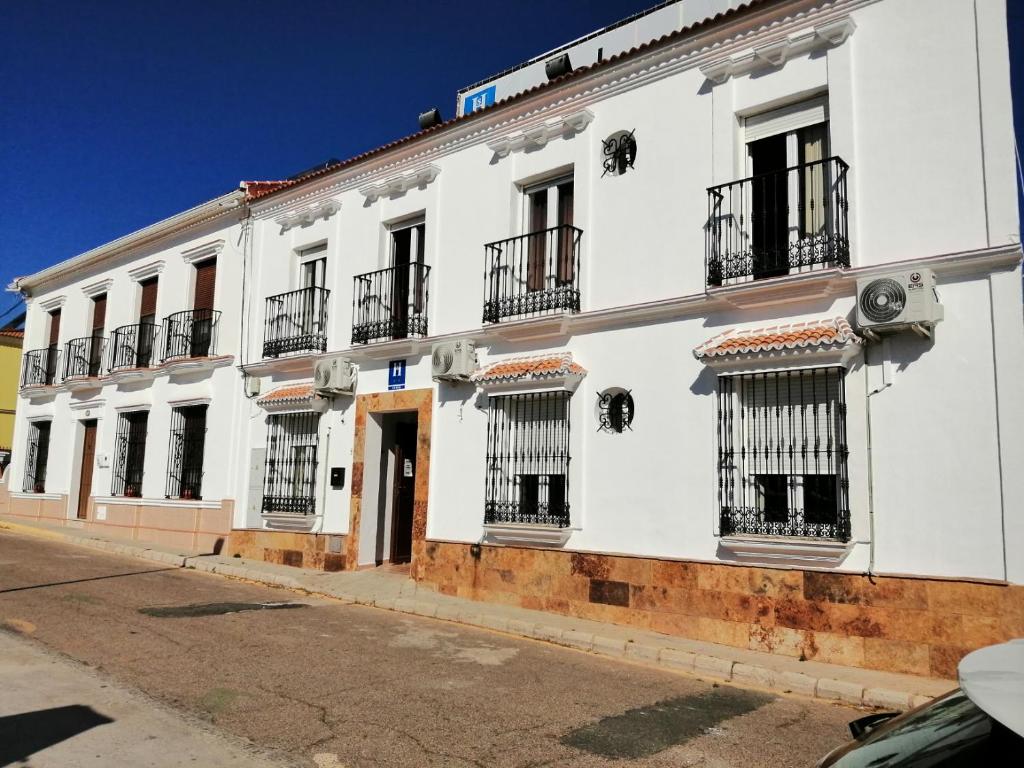 a white building with barred windows on a street at Hostal Alcarayón Pilas in Pilas