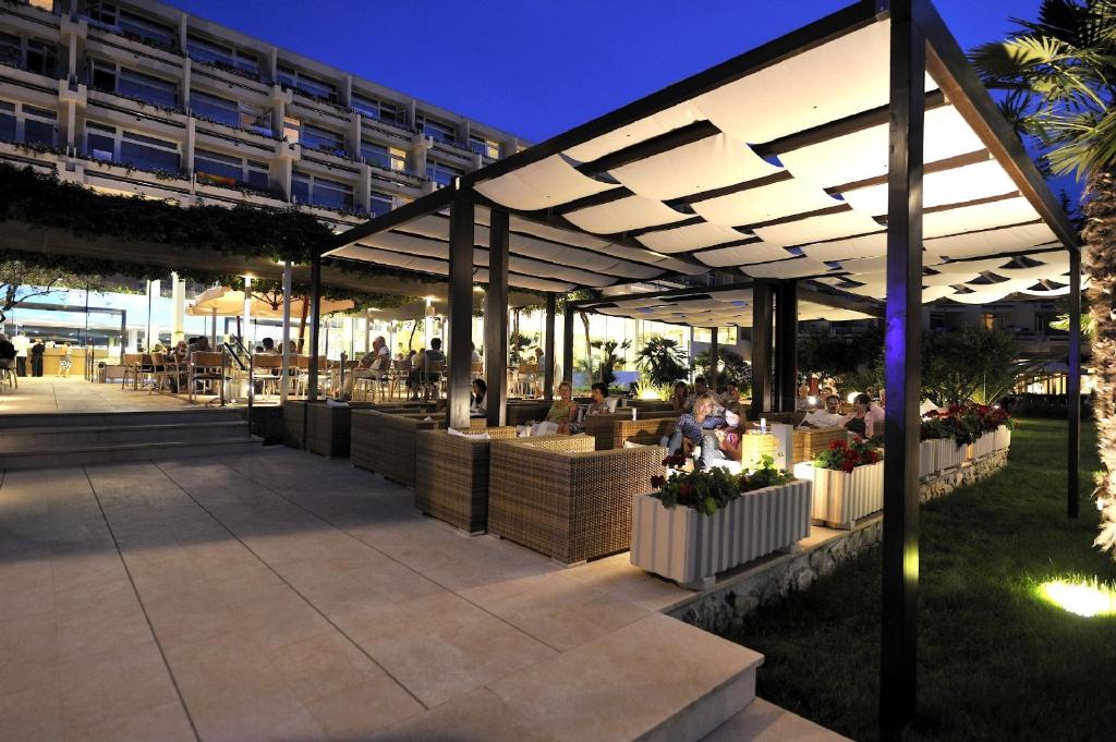 a patio with people sitting at tables under a pavilion at Hotel Mediteran Plava Laguna in Poreč