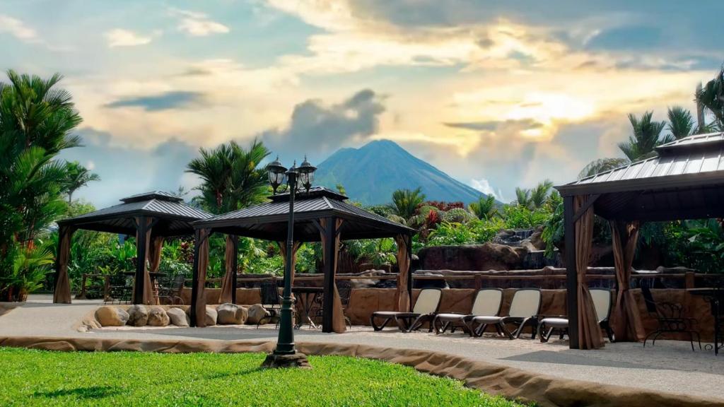 un patio con sillas, sombrillas y una montaña en Volcano Lodge, Hotel & Thermal Experience, en Fortuna