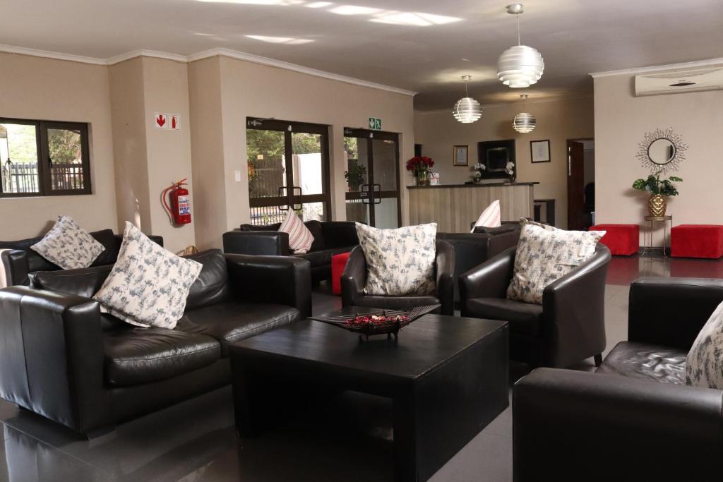 a living room with leather couches and a coffee table at Ruby Stone Boutique Hotel in Polokwane