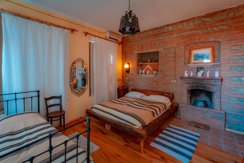 a bedroom with a brick wall with a bed and a fireplace at Dzveli Galavani -Old Wall in Tʼelavi