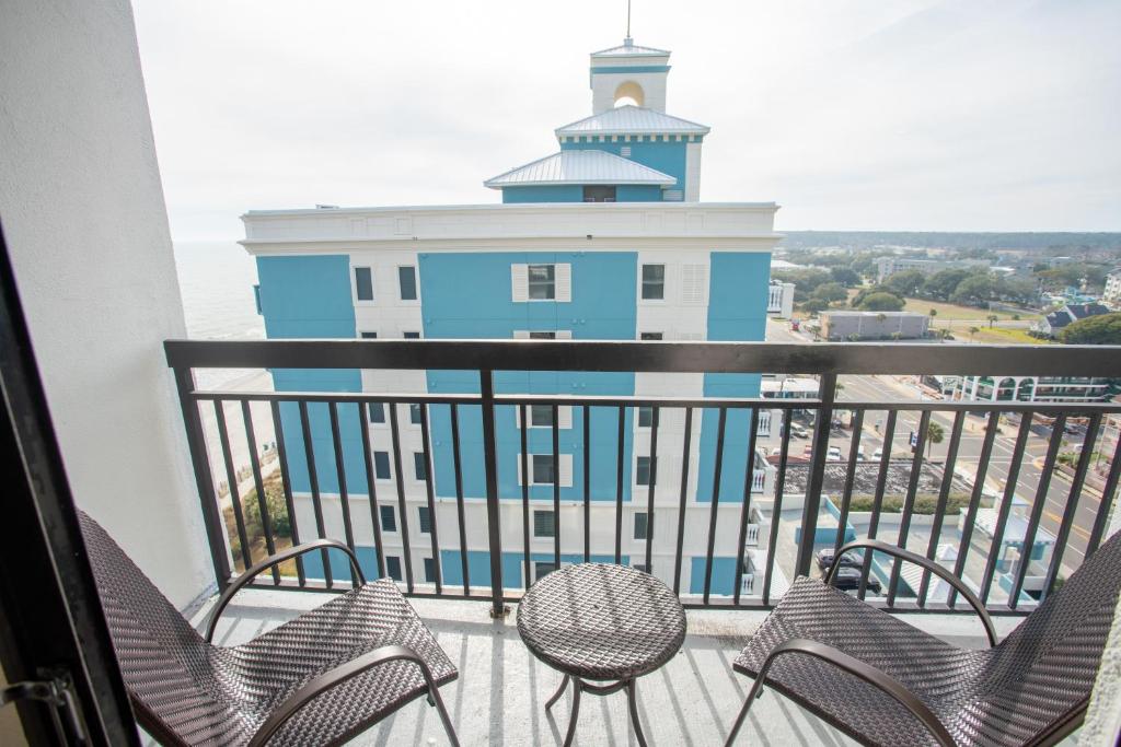 a balcony with chairs and a lighthouse in the background at Sun N Sand Resort in Myrtle Beach