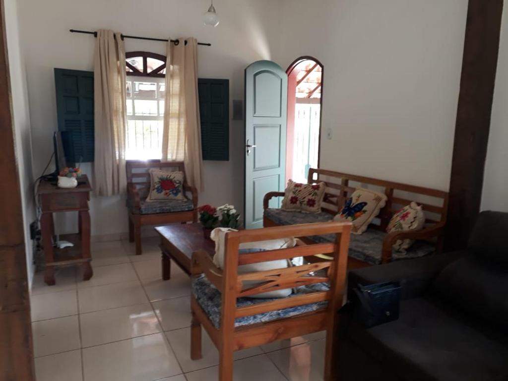 uma sala de estar com cadeiras, um sofá e janelas em Casa do Paulo da Santissima em Tiradentes