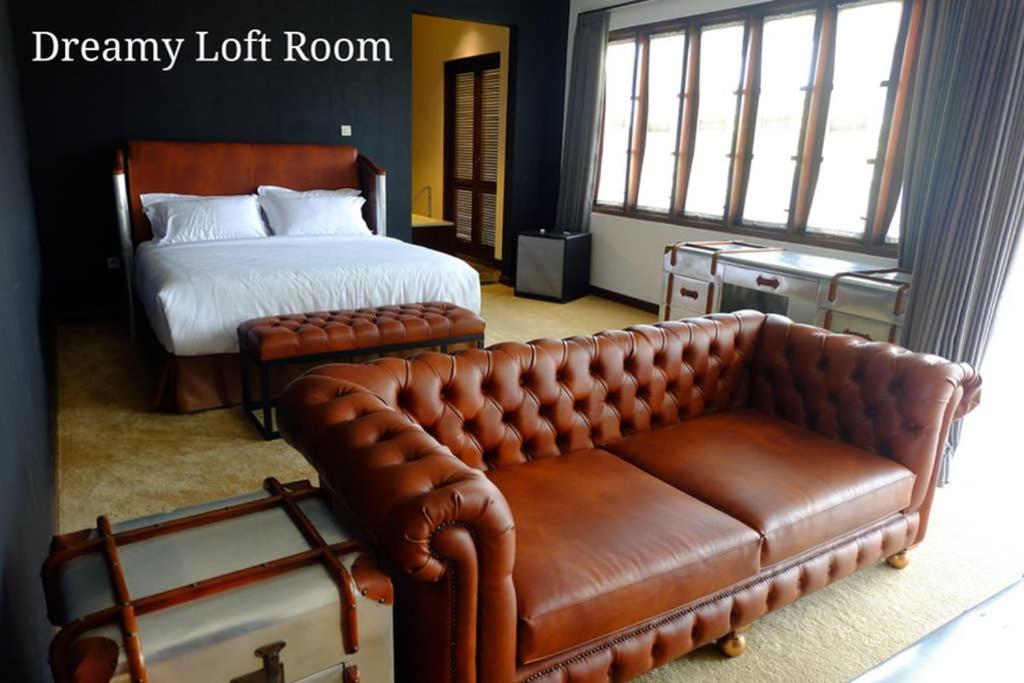 a bedroom with a bed and a leather couch at Dreamy Loft in Malang