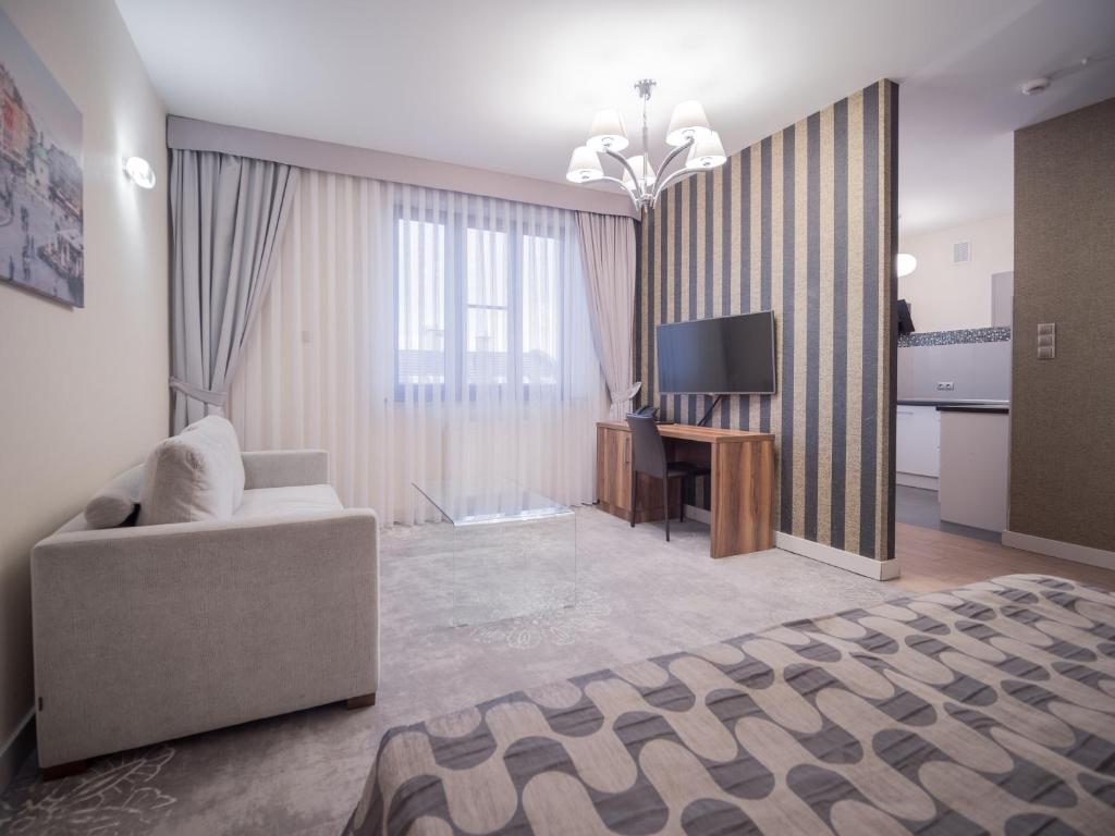 a bedroom with a couch and a desk and a television at Hotel Miodowa in Kraków