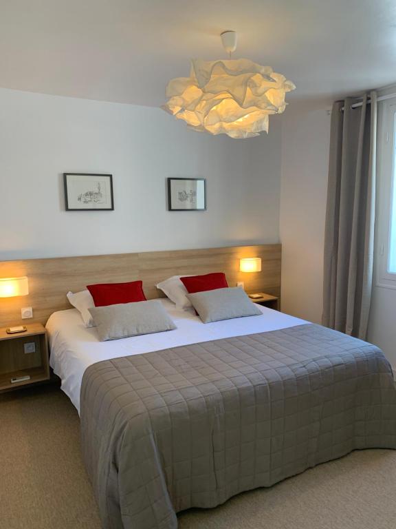 een slaapkamer met een groot bed en een kroonluchter bij Bel Appartement Terrasse 4 Étoiles Intra Muros in Aigues-Mortes