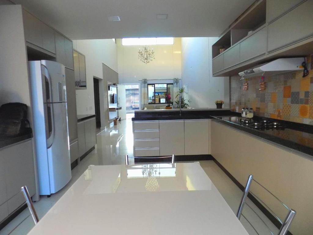 a large kitchen with white cabinets and a table in it at Casa NAIN in Foz do Iguaçu