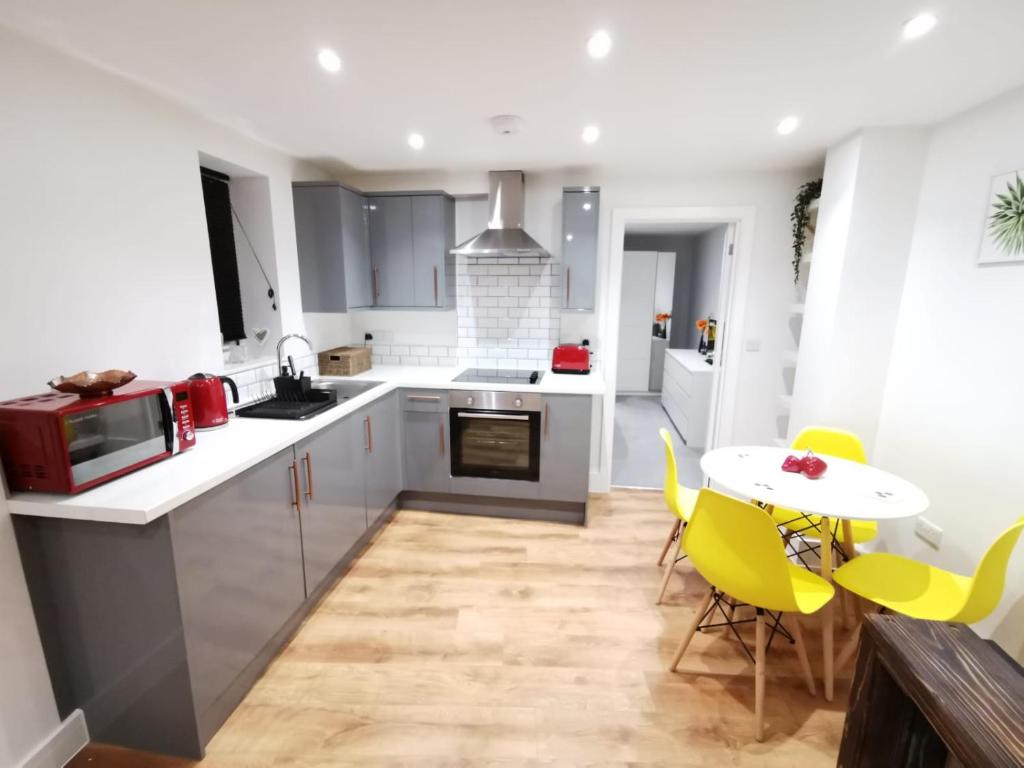 a kitchen with white cabinets and a table and chairs at 4 sleeps and travel cot- close to beach and restaurants in Bournemouth