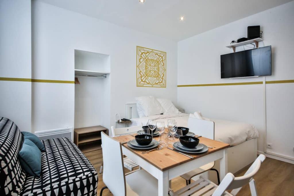 - un petit salon avec une table et un lit dans l'établissement cosy independant studio proche gare et jardin, à Paris