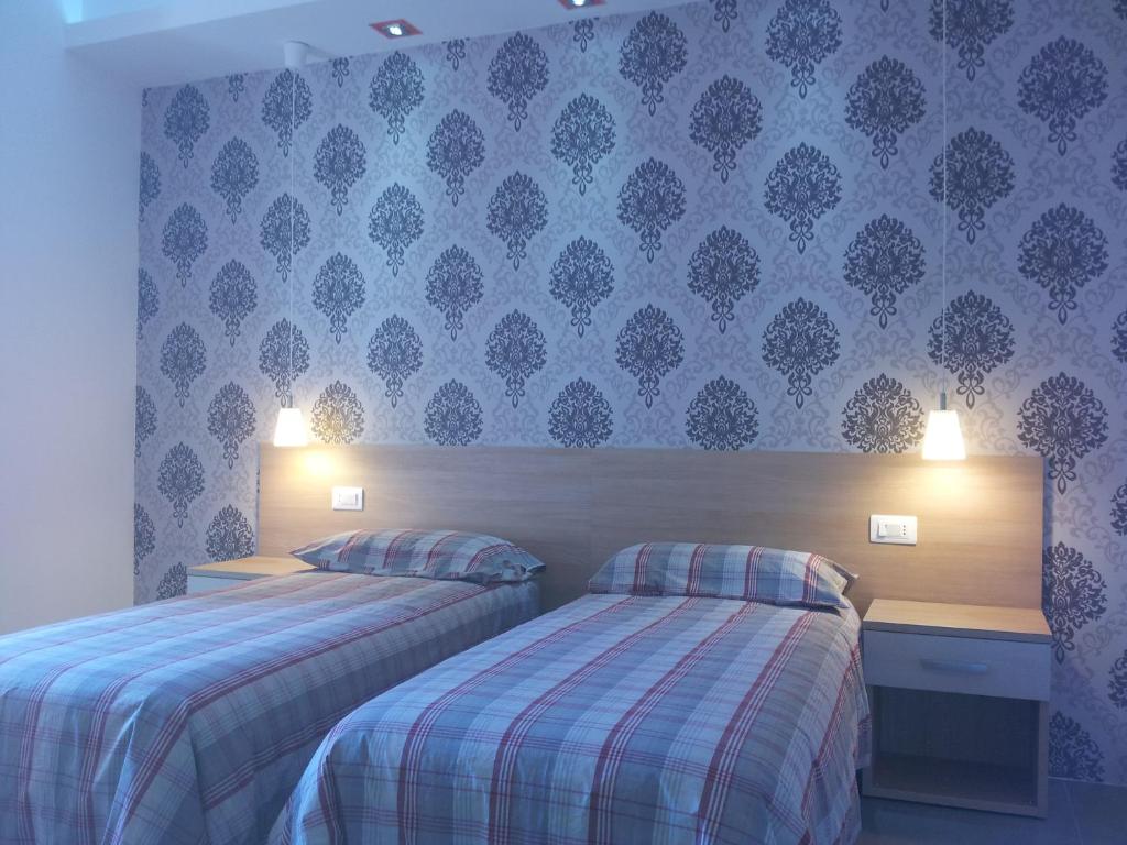 2 letti in una camera d'albergo con pareti blu di Borgo San Giovanni a Barcellona Pozzo di Gotto
