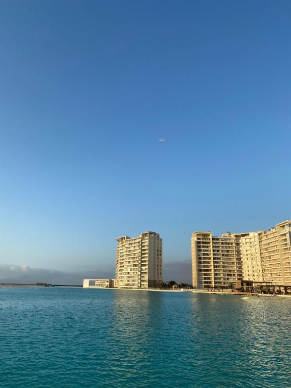 a group of tall buildings on a beach with water at La Serena Laguna del Mar hasta 8 personas espectacular departamento in La Serena