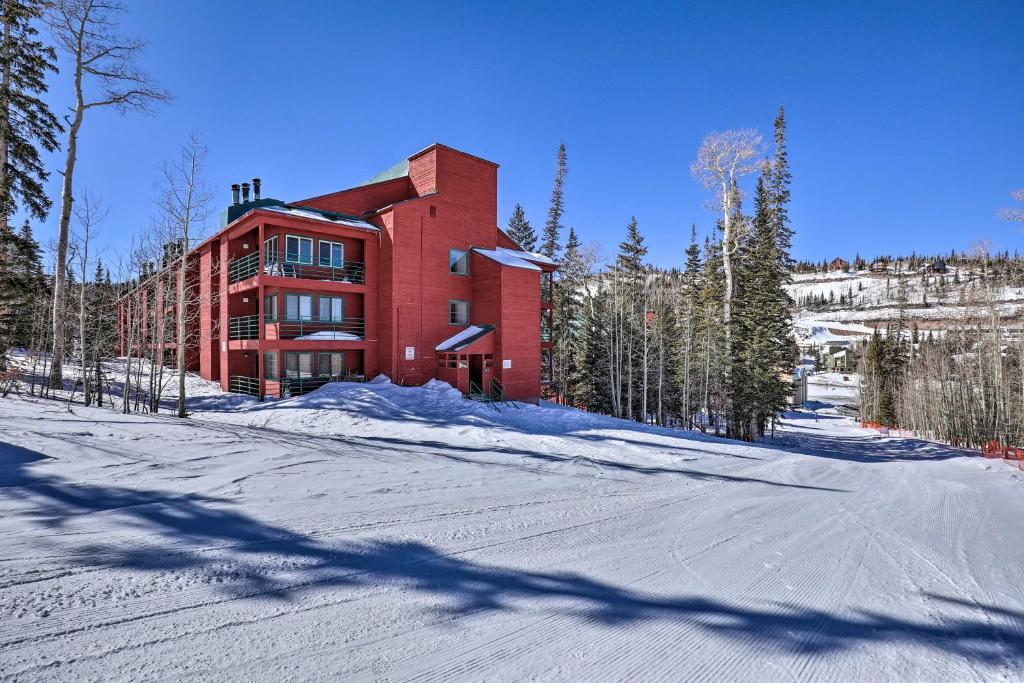 a red building on a snow covered street with trees at Brian Head Ski-InandSki-Out Condo with Resort Perks! in Brian Head