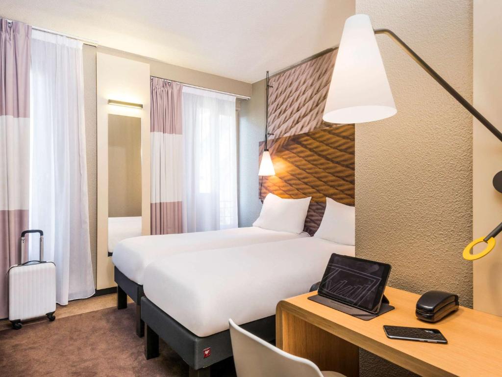 une chambre d'hôtel avec un grand lit et un bureau avec un bureau dans l'établissement ibis Clichy Centre Mairie, à Clichy