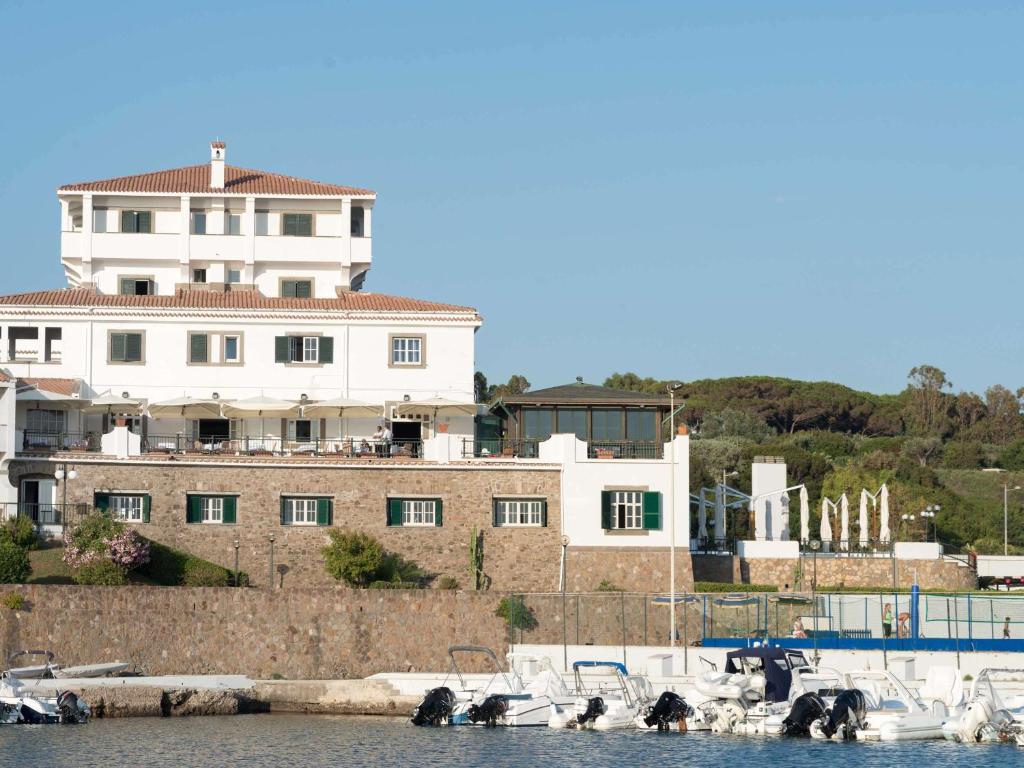 una gran casa blanca con barcos en el agua en Mercure Civitavecchia Sunbay Park Hotel, en Civitavecchia