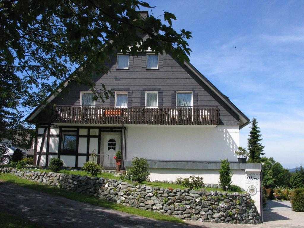 a large house with a balcony on top of a stone wall at Gästehaus Mira in Winterberg