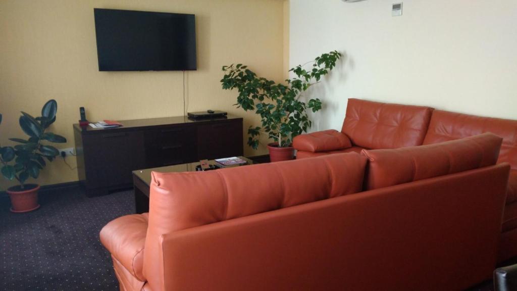 a living room with a red couch and a tv at AZIMUT Hotel Kemerovo in Kemerovo