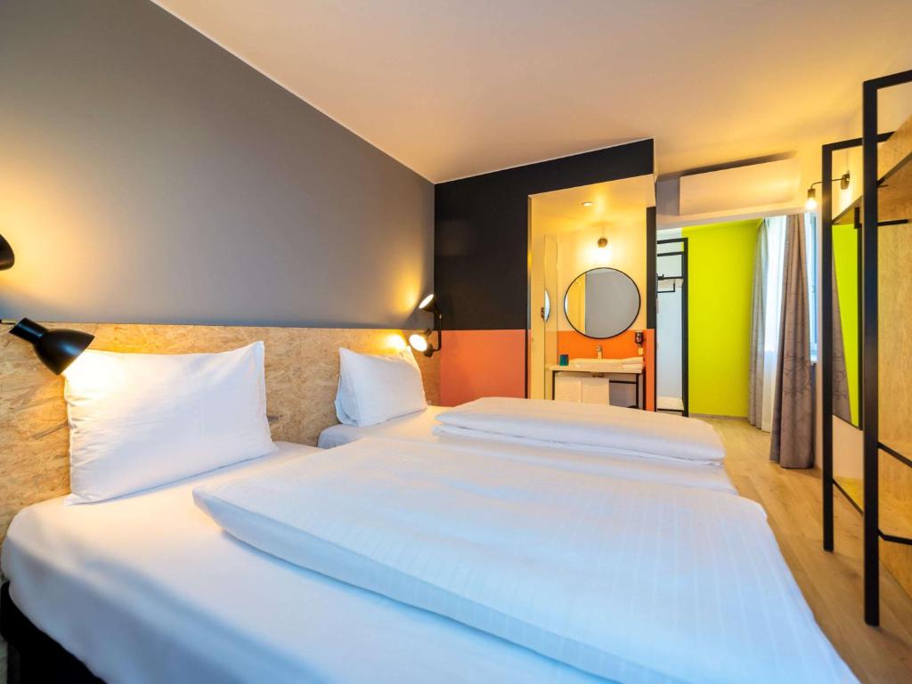 1 dormitorio con 2 camas y espejo en ibis Styles Wien Messe Prater en Viena