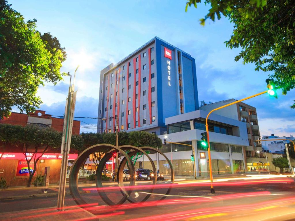 un alto edificio blu con una scultura di fronte a una strada di ibis Cucuta a Cúcuta