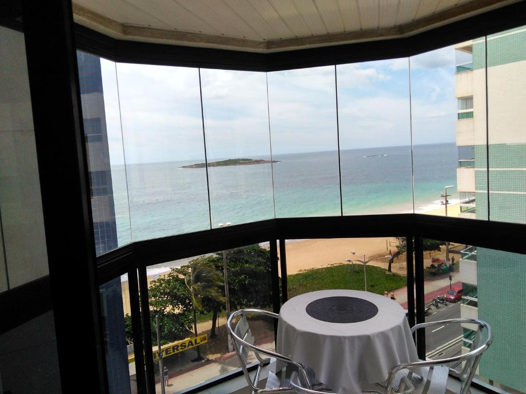 een tafel en stoelen in een kamer met uitzicht op de oceaan bij Residencial Atlanta in Vila Velha