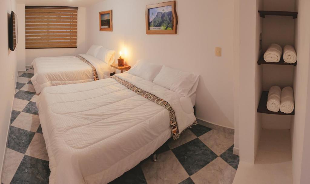 a room with two beds in a room with a checker floor at NOGAL HOSTEL in Pereira