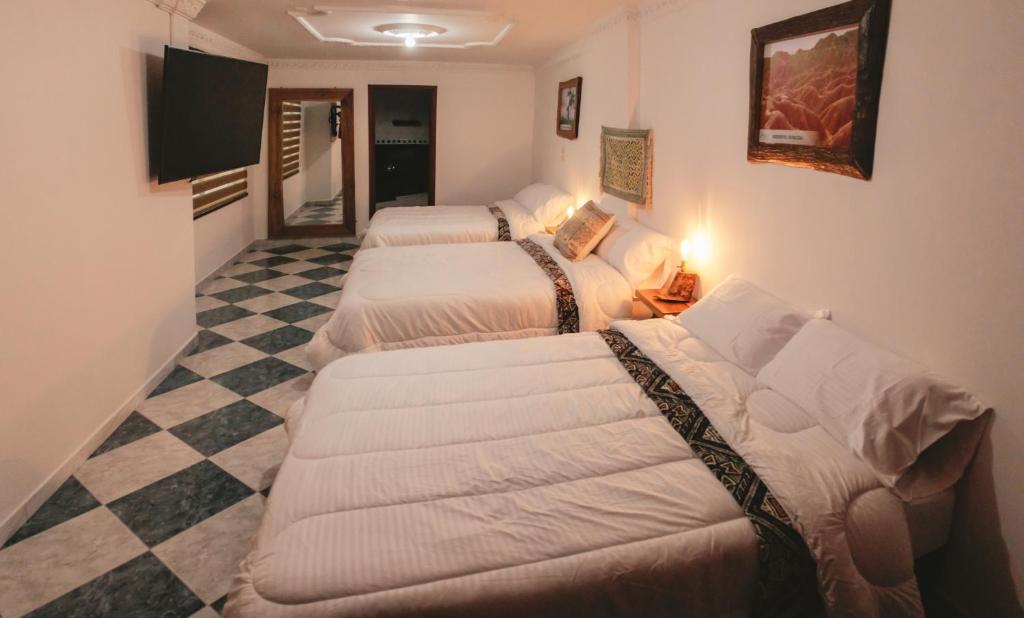 a hotel room with three beds and a checkered floor at NOGAL HOSTEL in Pereira