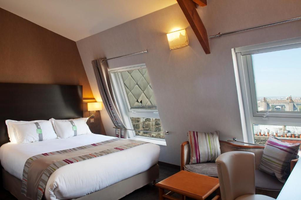 a hotel room with a bed and a chair and a window at Holiday Inn Paris Montmartre by IHG in Paris