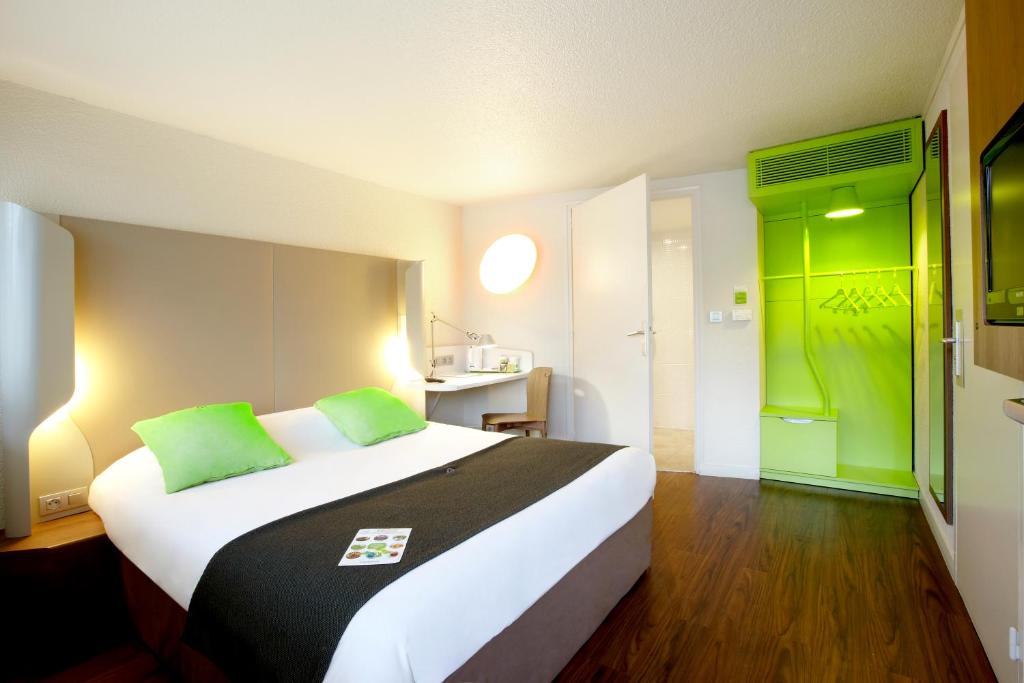 a bedroom with a large bed with green accents at Campanile Lille Nord Wasquehal in Wasquehal