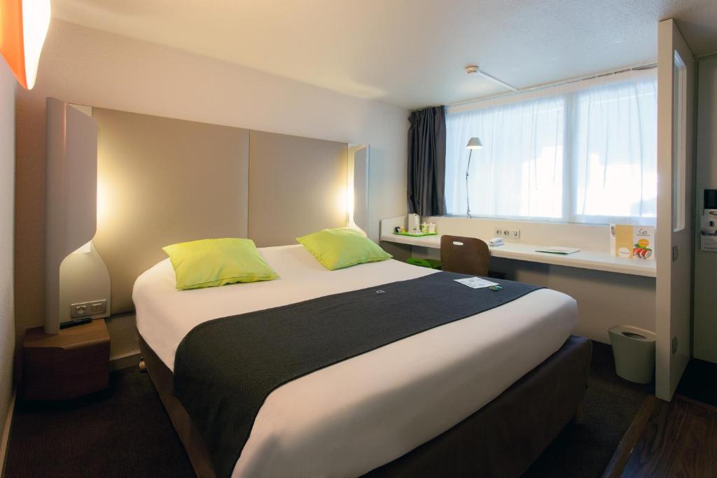 una camera d'albergo con un grande letto con cuscini gialli di Campanile Tours Sud ~ Joué-Les-Tours a Joué-lés-Tours