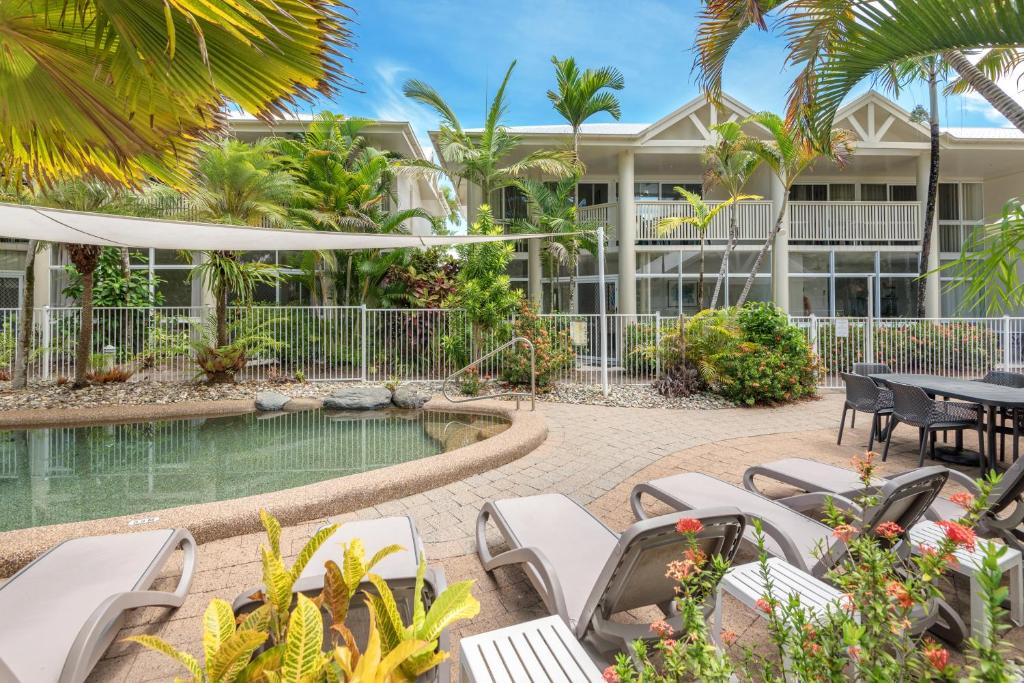 a resort with a pool and tables and chairs at Tropical Nites Holiday Townhouses in Port Douglas
