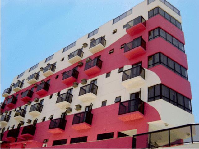 ein hohes rotweißes Gebäude mit vielen Fenstern in der Unterkunft Hotel Rosa Mar in Macaé