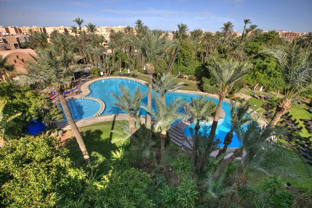 una vista aérea de una piscina del complejo con palmeras en Hôtel Marrakech Le Semiramis, en Marrakech