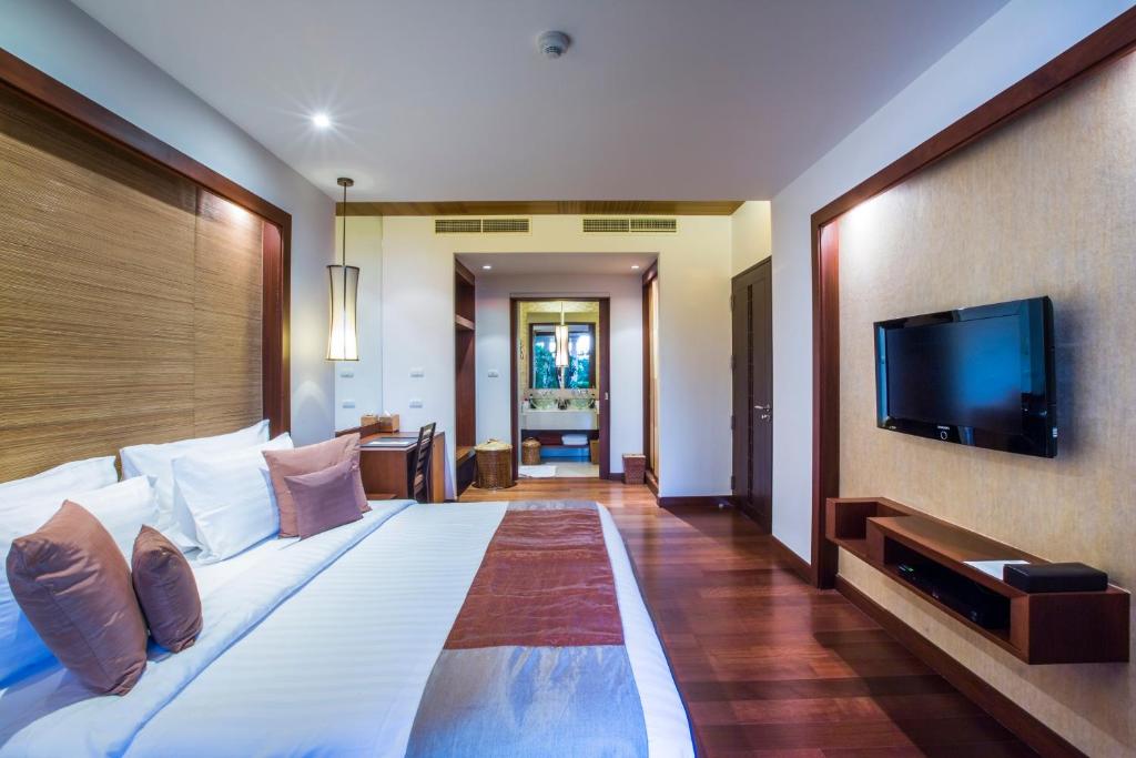a bedroom with a large bed and a flat screen tv at Mövenpick Resort Bangtao Beach Phuket in Bang Tao Beach
