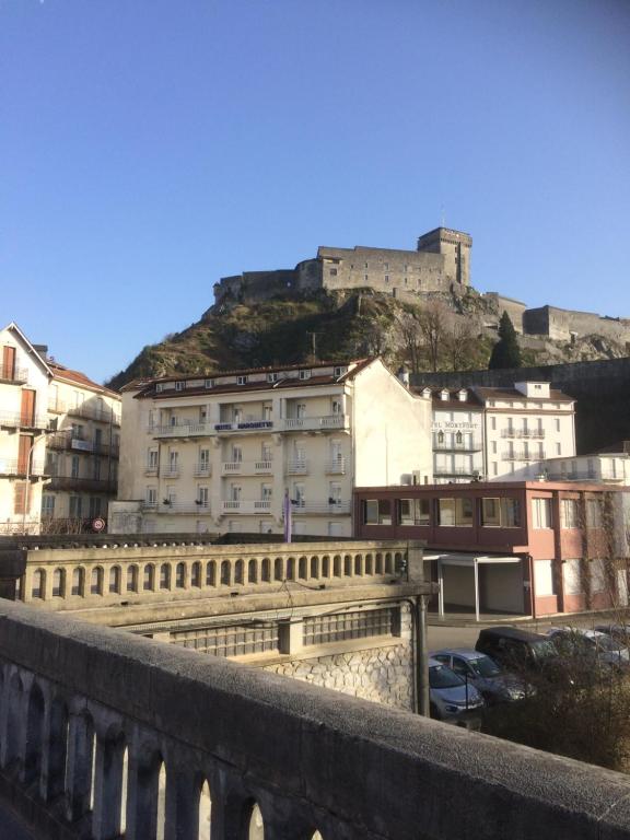 un bâtiment avec un château au sommet d'une colline dans l'établissement Hôtel Marquette, à Lourdes