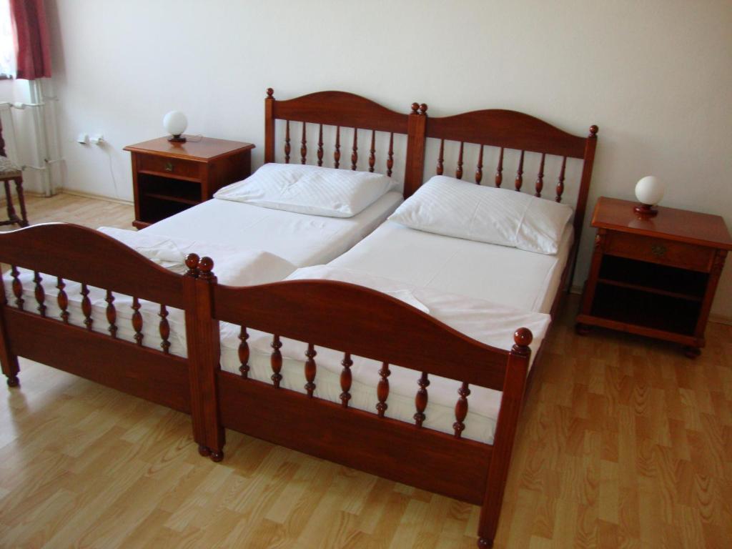 a large wooden bed with white sheets and pillows at Penzion Aviatik in Čáslav