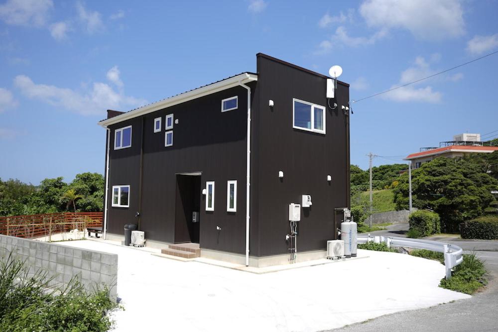 a black house sitting on the side of a street at Irie House Motobu in Motobu
